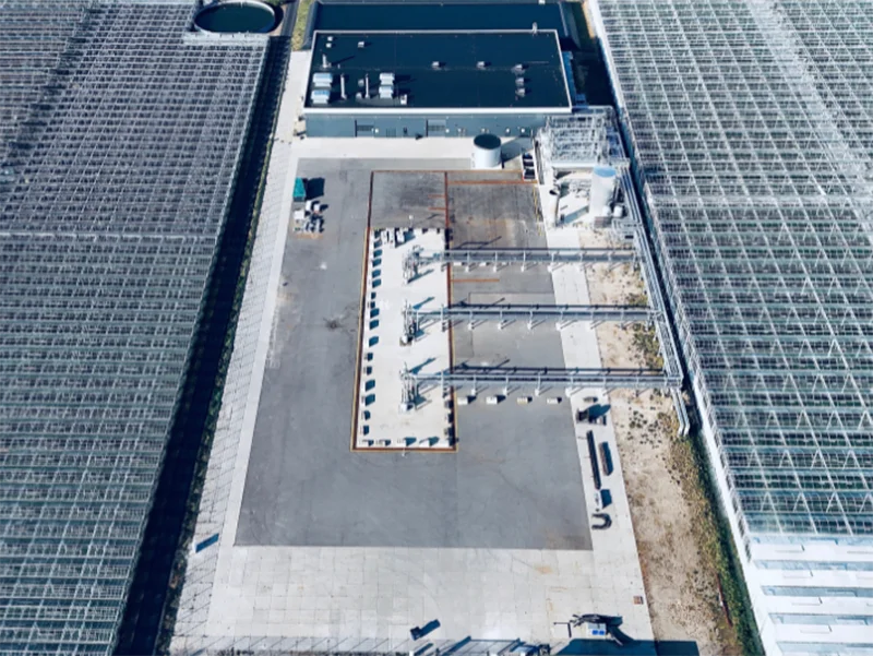aardwarmtecluster-maasdijk-bovenaf Luchtfoto van het aardwarmtecluster in Maasdijk, met kassen, een groot industrieel gebouw en installaties.