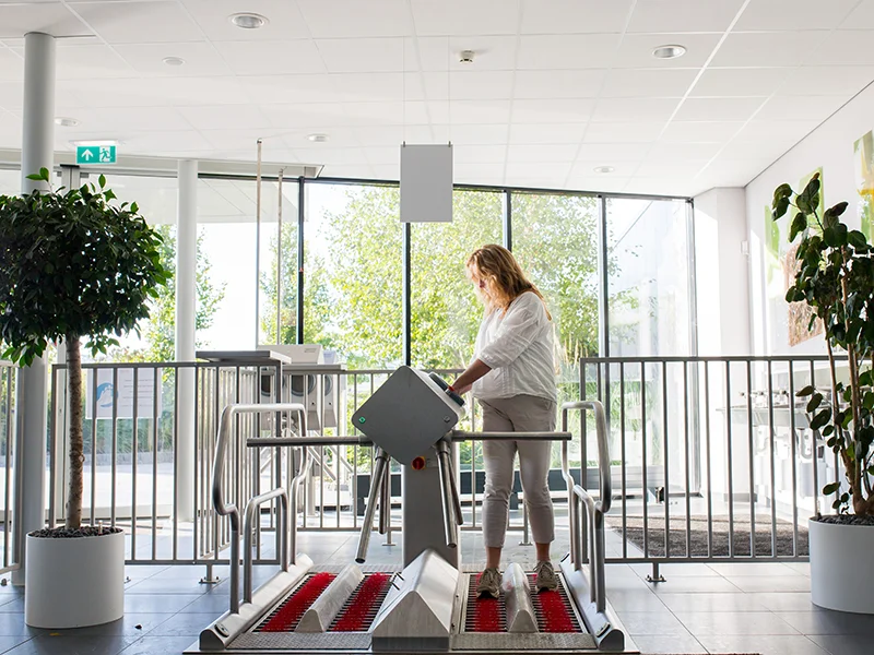 hygiene-station-entree Persoon die door het hygiënestation loopt bij de entree.